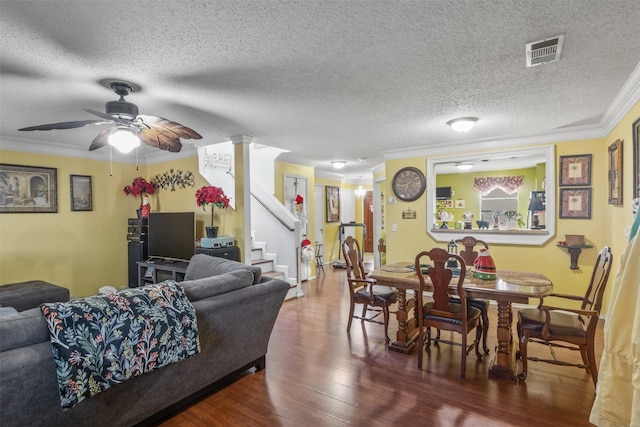 living room featuring ornate columns, ceiling fan, dark wood-type flooring, crown molding, and a textured ceiling