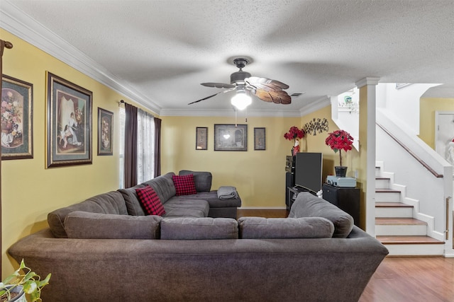 living room with hardwood / wood-style flooring, ceiling fan, ornamental molding, and a textured ceiling