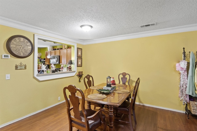 dining space featuring a textured ceiling, dark hardwood / wood-style flooring, and ornamental molding