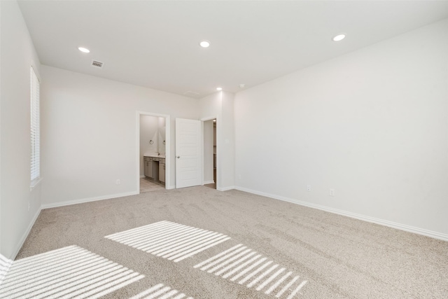 unfurnished bedroom featuring ensuite bathroom and light colored carpet