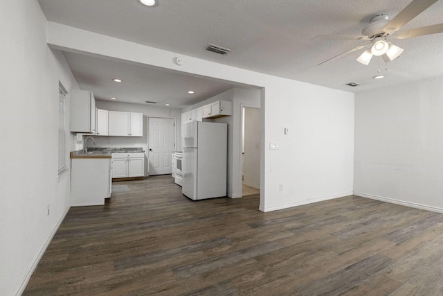 kitchen featuring ceiling fan, a textured ceiling, white fridge, dark hardwood / wood-style flooring, and white cabinetry