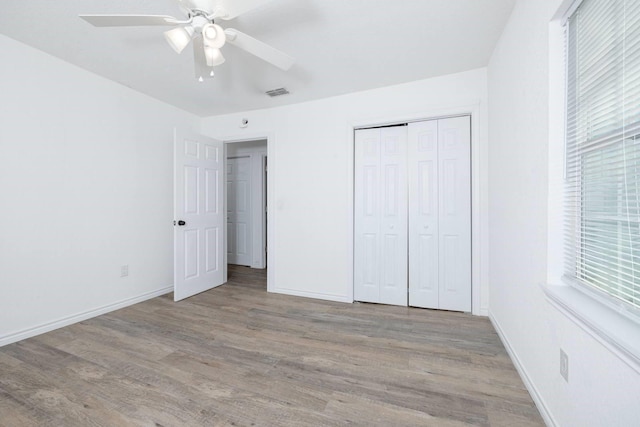 unfurnished bedroom with ceiling fan, multiple windows, light hardwood / wood-style flooring, and a closet