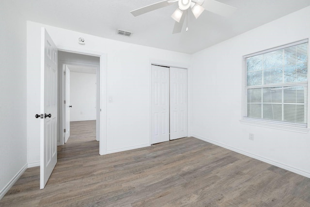 unfurnished bedroom with ceiling fan, wood-type flooring, and a closet