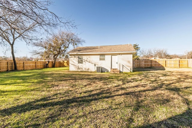 rear view of property featuring a lawn and central air condition unit