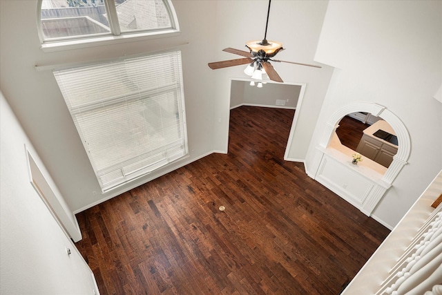 interior space with ceiling fan, a towering ceiling, and dark wood-type flooring