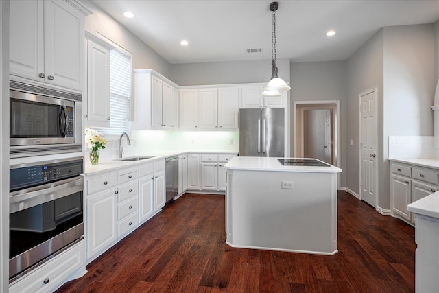 kitchen with white cabinetry, appliances with stainless steel finishes, hanging light fixtures, a kitchen island, and sink