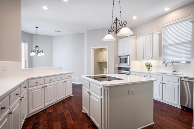 kitchen with pendant lighting, a center island, sink, white cabinetry, and appliances with stainless steel finishes