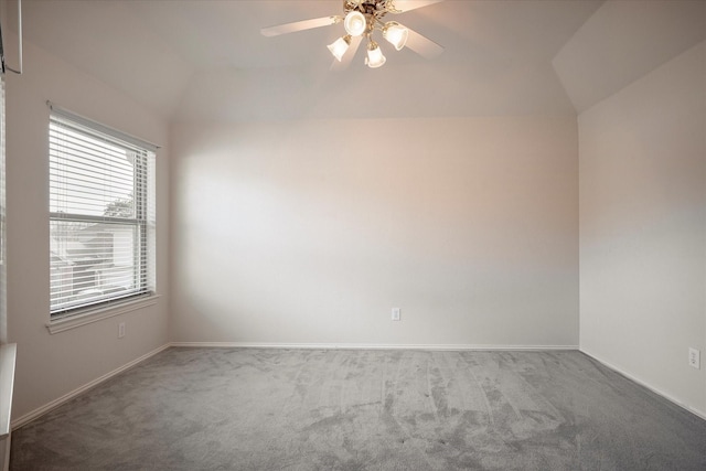 empty room with vaulted ceiling, ceiling fan, and carpet flooring