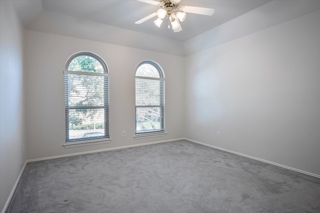 spare room with ceiling fan, carpet floors, a tray ceiling, and lofted ceiling