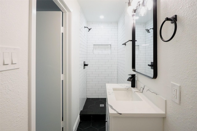 bathroom with a tile shower, tile patterned flooring, and vanity