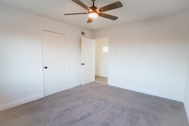 unfurnished bedroom featuring ceiling fan, a closet, and light carpet