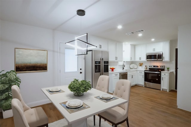 dining space with sink and light hardwood / wood-style floors