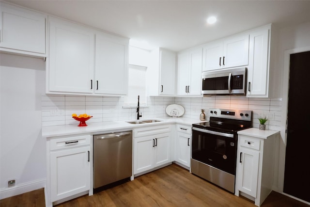 kitchen with decorative backsplash, appliances with stainless steel finishes, dark wood-type flooring, sink, and white cabinets