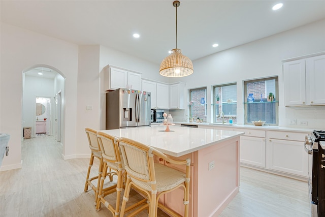 kitchen featuring white cabinets, appliances with stainless steel finishes, a kitchen island, and hanging light fixtures