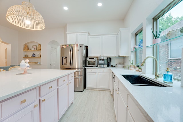 kitchen with stainless steel fridge, white cabinetry, and hanging light fixtures