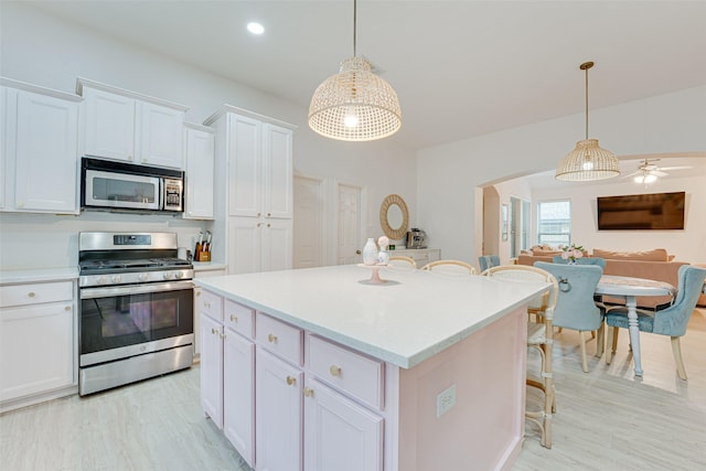 kitchen with white cabinetry, hanging light fixtures, ceiling fan, and stainless steel appliances