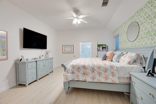 bedroom featuring ceiling fan, vaulted ceiling, ensuite bathroom, and light hardwood / wood-style flooring