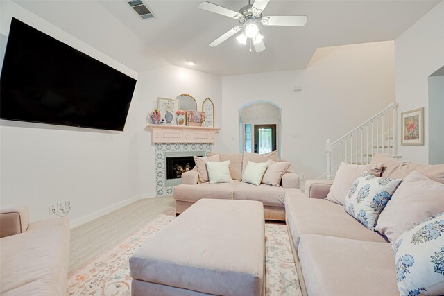 living room with ceiling fan, light hardwood / wood-style floors, and vaulted ceiling