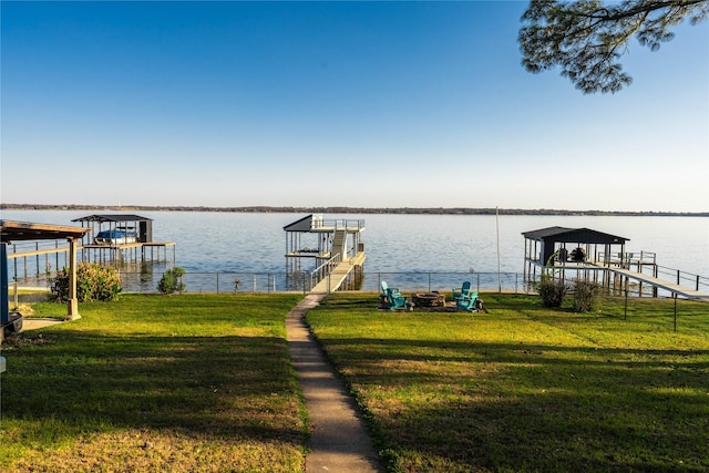 view of dock with a yard, a water view, and an outdoor fire pit