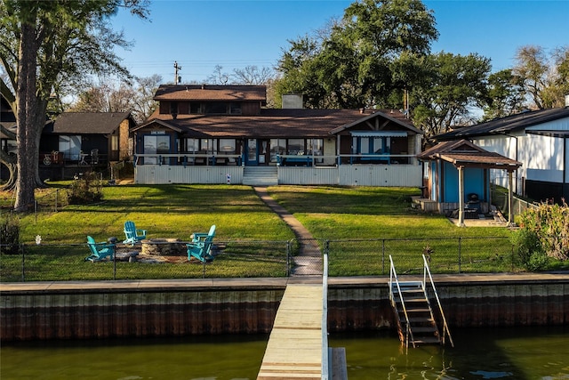 back of property with a yard, a water view, and an outdoor fire pit