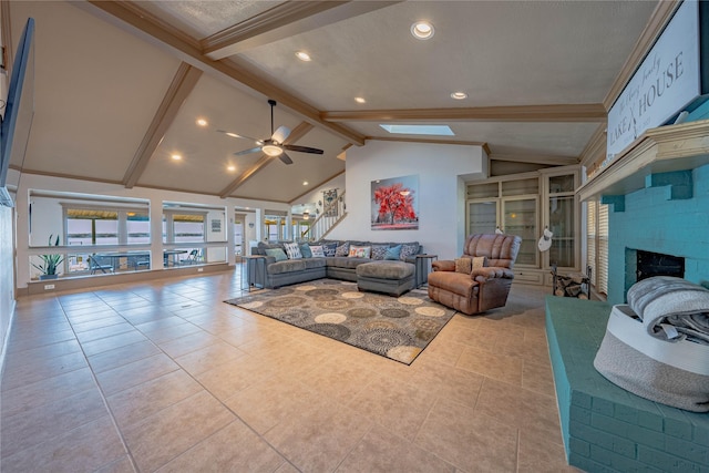 living room featuring ceiling fan, a brick fireplace, beamed ceiling, high vaulted ceiling, and light tile patterned floors