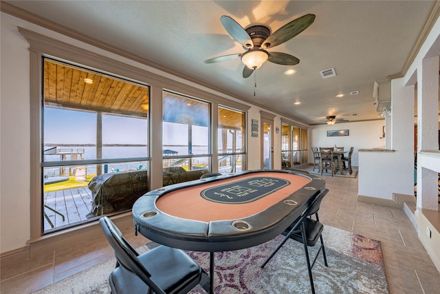 rec room featuring ceiling fan, a water view, light tile patterned floors, and crown molding