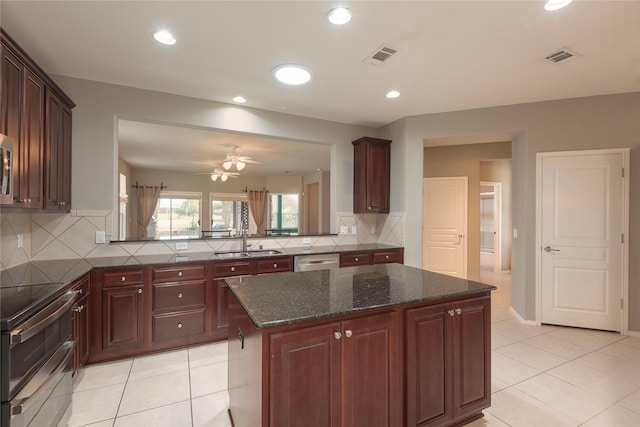 kitchen with sink, a center island, stainless steel dishwasher, dark stone countertops, and range