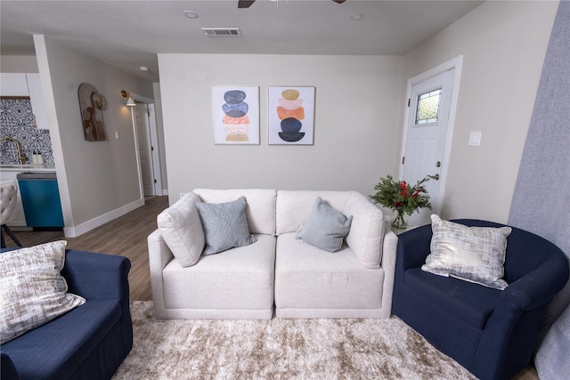 living room with hardwood / wood-style floors, ceiling fan, and sink