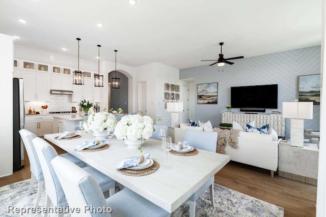 dining space with hardwood / wood-style floors and ceiling fan with notable chandelier