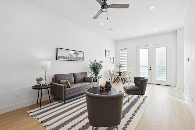 living room featuring french doors, ceiling fan, and light wood-type flooring