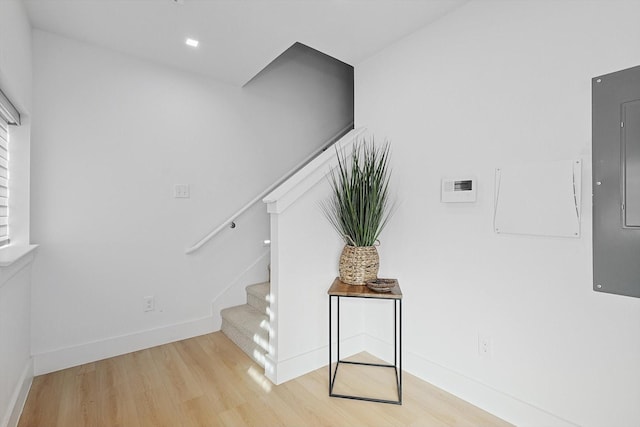 stairway with hardwood / wood-style floors and electric panel