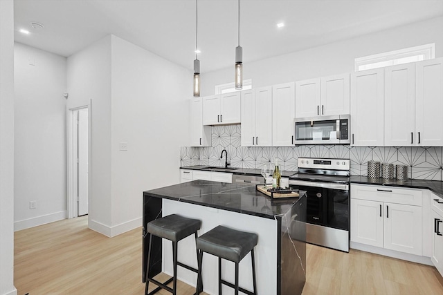 kitchen with decorative light fixtures, sink, a breakfast bar area, a center island, and stainless steel appliances