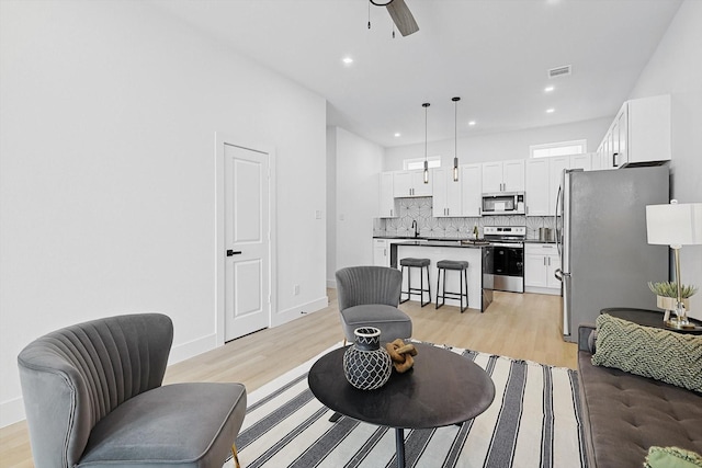 living room with sink, light hardwood / wood-style flooring, and ceiling fan