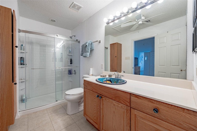 bathroom with tile patterned floors, toilet, a shower with shower door, a textured ceiling, and vanity