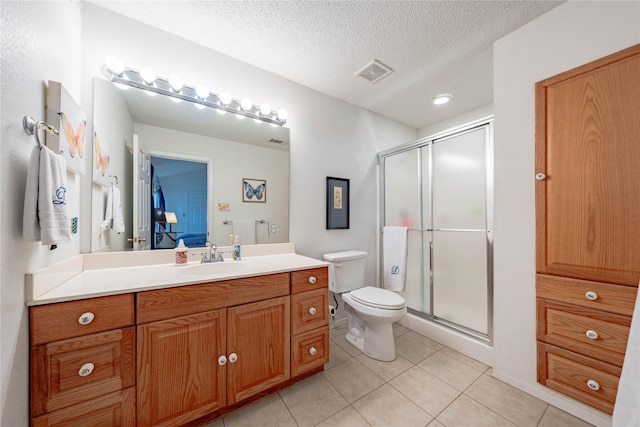 bathroom featuring vanity, tile patterned flooring, a shower with door, and a textured ceiling