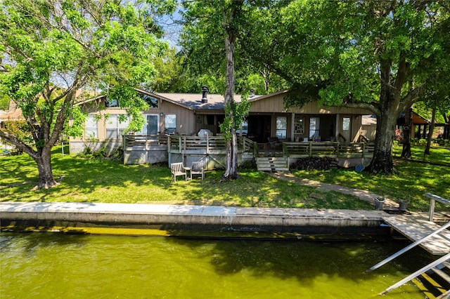 back of house with a lawn and a water view