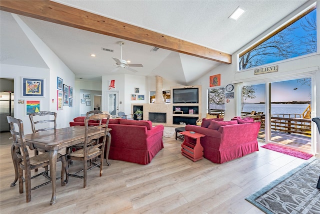 living room with a ceiling fan, visible vents, vaulted ceiling with beams, and light wood-type flooring