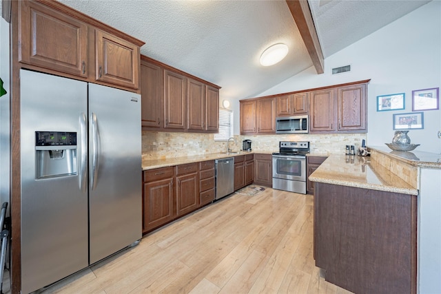 kitchen featuring kitchen peninsula, tasteful backsplash, stainless steel appliances, sink, and vaulted ceiling with beams