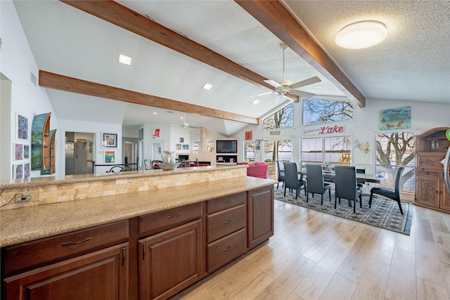 kitchen featuring beam ceiling, ceiling fan, light stone countertops, a textured ceiling, and light wood-type flooring