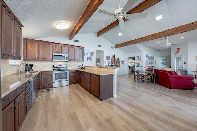 kitchen featuring stainless steel appliances, a ceiling fan, open floor plan, and a sink