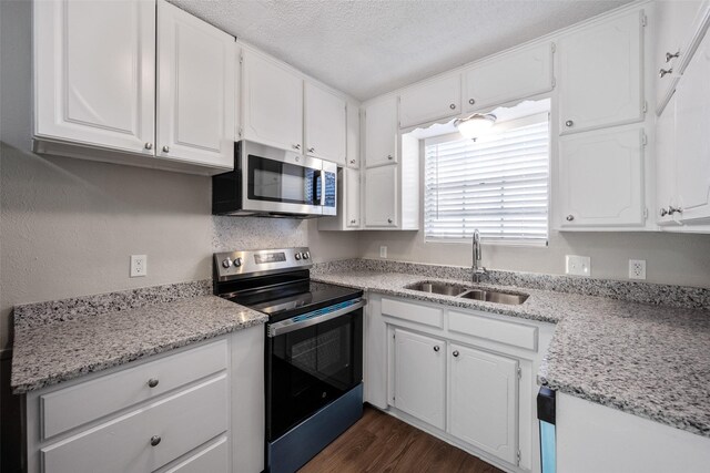 kitchen with a textured ceiling, stainless steel appliances, white cabinetry, and sink