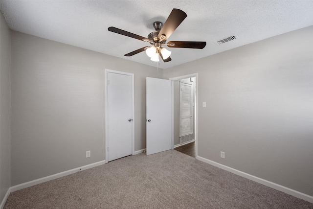 unfurnished bedroom with ceiling fan, a textured ceiling, and dark colored carpet