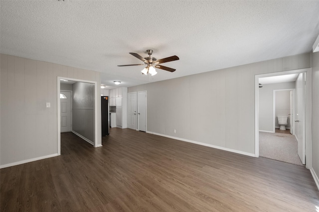 unfurnished living room featuring dark hardwood / wood-style floors, ceiling fan, and a textured ceiling