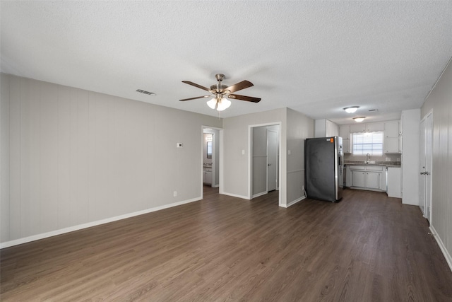 unfurnished living room with dark hardwood / wood-style floors, ceiling fan, and a textured ceiling