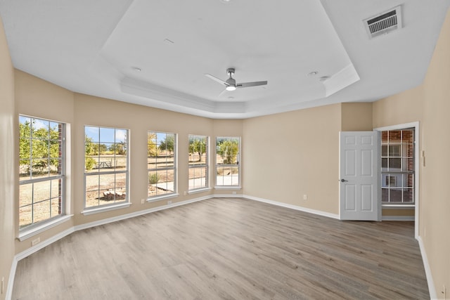 spare room featuring ceiling fan, hardwood / wood-style floors, a wealth of natural light, and a raised ceiling