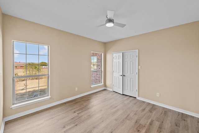 unfurnished bedroom with ceiling fan, a closet, multiple windows, and light hardwood / wood-style floors