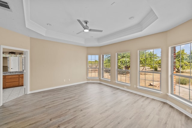 spare room with light hardwood / wood-style floors, a tray ceiling, and ceiling fan