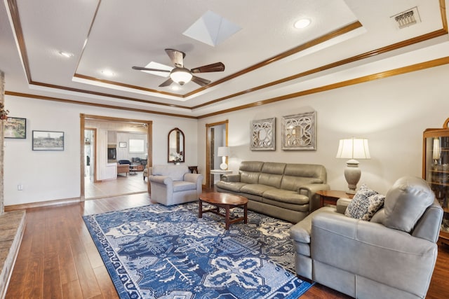 living room with hardwood / wood-style flooring, a tray ceiling, and ornamental molding