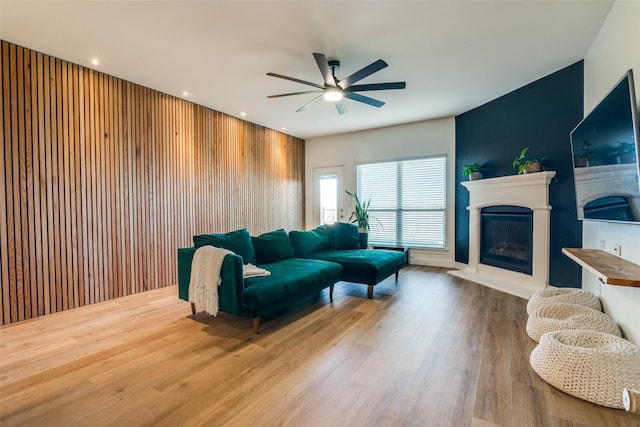 living room featuring hardwood / wood-style floors, ceiling fan, and wood walls