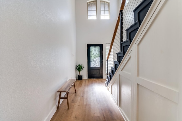 entrance foyer featuring light hardwood / wood-style floors and a towering ceiling